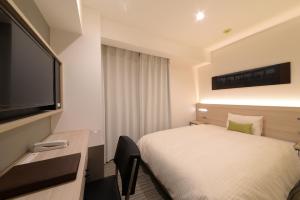 a hotel room with a bed and a flat screen tv at Vessel Inn Shinsaibashi in Osaka