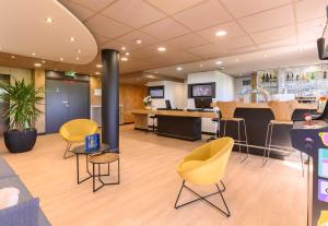 a lobby with yellow chairs and a bar at B&B HOTEL Versailles Le Chesnay in Le Chesnay
