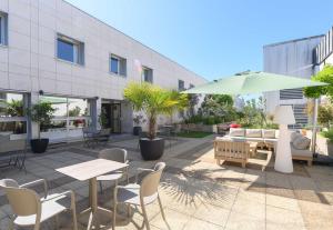 a patio with tables and chairs and an umbrella at B&B HOTEL Versailles Le Chesnay in Le Chesnay