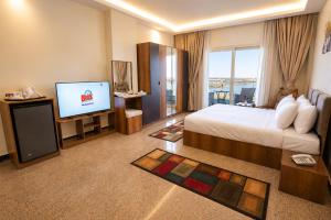 a hotel room with a bed and a flat screen tv at Blue Lotus Nile Suites Hotel Aswan in Aswan