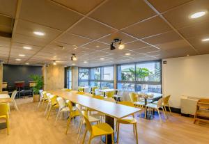 a conference room with a long table and yellow chairs at B&B HOTEL Versailles Le Chesnay in Le Chesnay
