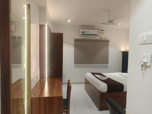 a bedroom with a bed and a desk in a room at Hotel Tals Hytek in Hyderabad +9 photos