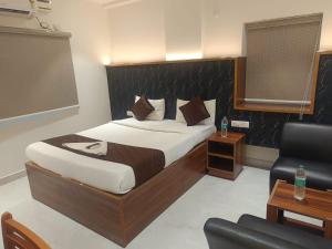 a bedroom with a large bed and a chair at Hotel Tals Hytek in Hyderabad