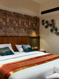 a bedroom with a large bed with blue pillows at Hosta Inn Hotel and Resort in Edappāl +39 photos