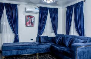 a blue couch in a living room with blue curtains at Smile Apartment in Ilishan