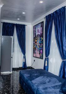 a bedroom with blue curtains and a blue bed at Smile Apartment in Ilishan