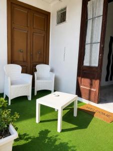 two white chairs and a table and a door at Station Comfort House in Pagani