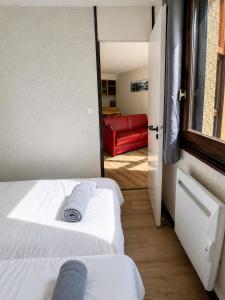 a bedroom with two beds and a red couch at L'évasion montagnarde - résidence loisirs - garage in Lélex