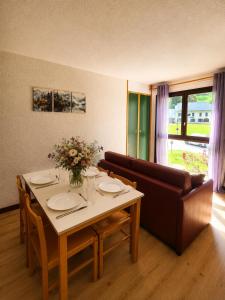 a dining room with a table and a couch at L'évasion montagnarde - résidence loisirs - garage in Lélex