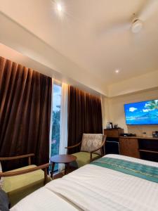a hotel room with a bed and a flat screen tv at Hosta Inn Hotel and Resort in Edappāl