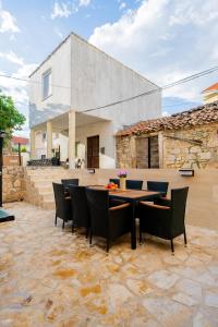 a patio with a table and chairs and a building at Loro House & Jacuzzi in Posedarje