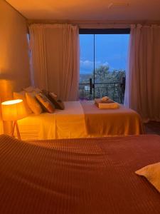 a bedroom with two beds and a window with a view at Govinda House in Alto Paraíso de Goiás