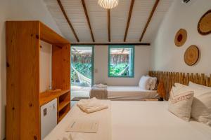 a bedroom with two beds and a window at Pousada do Rio Caraíva in Caraíva