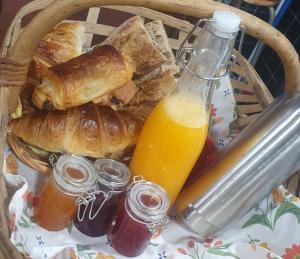 a basket of bread and croissants and a bottle of orange juice at Roulotte bohème in Chazelles