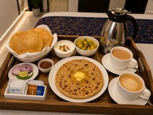 a tray of breakfast food with cups of coffee and toast at Hotel Bellamontan Suites Near Delhi Airport - Free Airport Pickup & Drop in New Delhi +19 photos