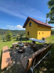 a yellow house with a picnic table and a fire pit at Slnečný dvor Bukovinka in Dravce