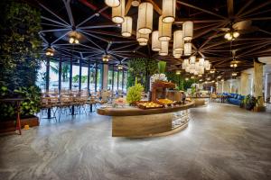 a restaurant with tables and chairs and a large ceiling at Flamingo Cát Bà Sea Residence , Sky Villa Premier Ocean View King Bed in Hai Phong