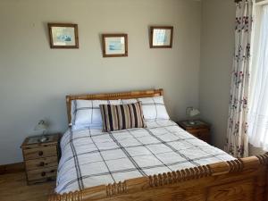 a bedroom with a bed with a wooden headboard and two windows at St Ann's Rossbeigh in Glenbeigh