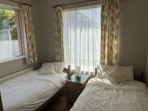 two twin beds in a room with a window at St Ann's Rossbeigh in Glenbeigh