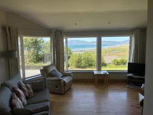 a living room with a couch and two large windows at St Ann's Rossbeigh in Glenbeigh