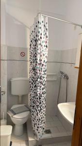a bathroom with a toilet and a shower curtain at Roula's Apartment in Limenaria