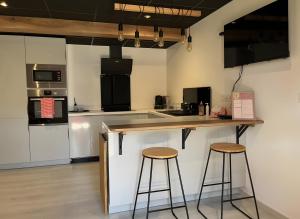 a kitchen with two bar stools and a counter top at Appartement Gorges du Tarn in Mostuéjouls