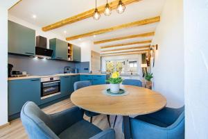 a kitchen with a wooden table and blue chairs at Ferienhaus Maarruhe in Schalkenmehren