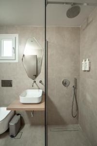 a bathroom with a shower with a sink and a mirror at Sokrates Studios in Afantou
