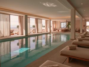 a pool in a hotel with lounge chairs and windows at Besai Ibiza Boutique Hotel - New Opening in San Jose