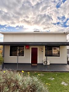 a white house with a red door on a deck at Fleur de Collie in Collie