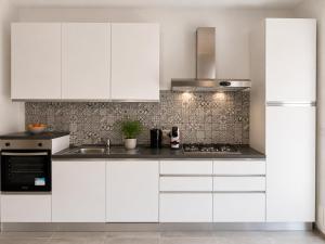 a white kitchen with white cabinets and a sink at Urban charme loft in Dorgali