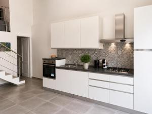 a kitchen with white cabinets and a stove at Urban charme loft in Dorgali