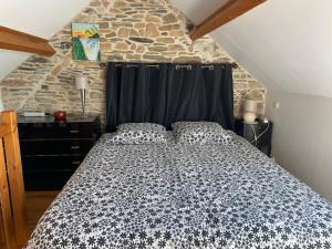 a bed in a room with a stone wall at Gite du Becquet in Le Rozel