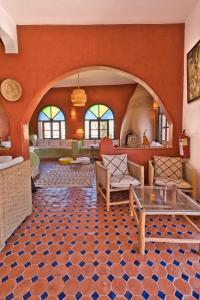 a living room with orange walls and a tile floor at Villa Nouran - Chambre D'Hôte in Ghazoua