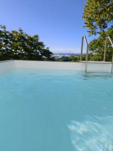 a swimming pool with blue water and trees in the background at appartement Barbera in Castel Rocchero