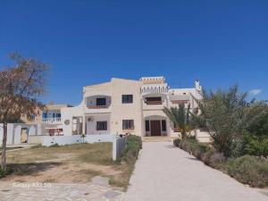 a large white house with a pathway in front of it at Résidence Kyranis appartement Noix de Coco in Sfax