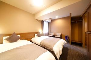 a hotel room with two beds and a window at Dormy Inn Toyama Natural Hot Spring in Toyama