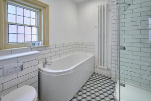 a white bathroom with a tub and a toilet at Sandy Toes in Sandsend +17 photos