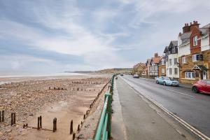 a street next to a beach with houses and cars at Sandy Toes in Sandsend