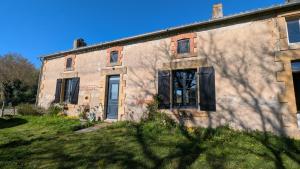 an old brick building with black shutters on it at La demeure de vos désirs in Pressac