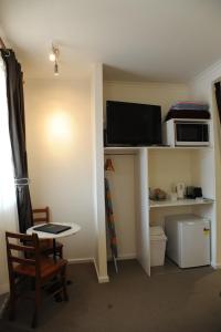 a living room with a tv and a microwave on a shelf at Norwood House Motel & Receptions in Mornington