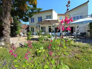 a garden with pink flowers in front of a building at Hôtel Le P'tit Monde in Montignac