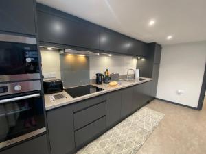 a kitchen with black cabinets and a sink and a stove at The Courtyard Apartment, Brampton Town Centre, Hadrians Wall - Sleeps 2 in Brampton
