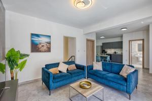 a living room with two blue couches and a table at Spacious and refined 3 bedroom duplex KARP1-1 in San Ġwann