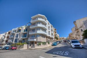 a tall apartment building with cars parked on the street at Spacious and refined 3 bedroom duplex KARP1-1 in San Ġwann