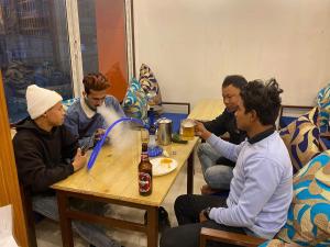 a group of men sitting around a table with a dog at Peace Hostel in Kathmandu