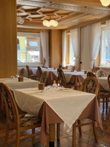 ein Esszimmer mit Tischen und Stühlen mit weißer Tischdecke in der Unterkunft Hotel Ideal in Sarche di Calavino + 21 Fotos