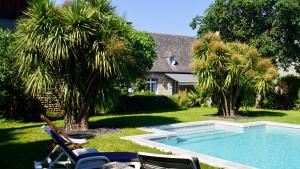a yard with a swimming pool with chairs and palm trees at Maison Thoumieu in Azereix