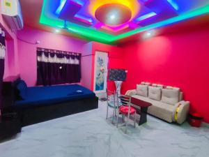 a living room with a couch and a pink wall at Hotel Happy House in kolkata +7 photos