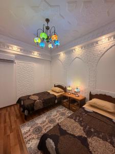 a room with two beds and a chandelier at GUZAL Hotel PREMIUM in Bukhara